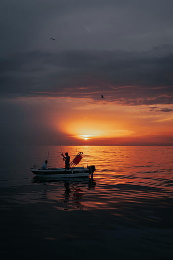 sunset, fishermen, boat, calm waters, dramatic skies, peaceful sunset, fishing trip, ocean, silhouettes, birds, evening