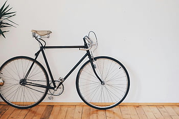 vélo noir à engrenage fixe, vélo de style vintage, mur blanc propre, plancher en bois, design minimaliste, vélo penché, vélo intérieur, vélo noir, mur blanc, sol en bois, décor minimaliste
