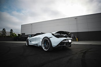 white McLaren, sportscar, asphalt surface, luxurious supercar, open trunk, industrial parking lot, daytime, high-performance vehicle, sleek design, modern car, automotive photography