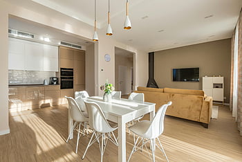 jídelní stůl, židle, kuchyně, moderní design, přirozené osvětlení, Prostorný obývací pokoj, Současný interiér, Rozložení otevřeného plánu, Bílý nábytek, dřevěná podlaha, přívěsek světla