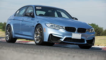 blue sedan, luxury car, tarmac racing circuit, daylight, sleek design, BMW, racing track, high-performance vehicle, automotive photography, car enthusiasts, daytime driving