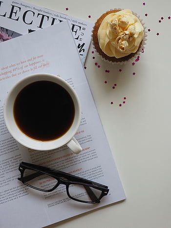 coffee break setup, white ceramic cup, opened book, eyeglasses, cupcake, magazine, top view, elegant lifestyle, coffee, cup, glasses