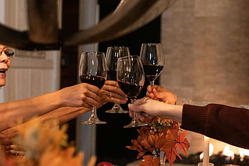 persone che tifano, bicchieri di vino, vino rosso, Celebrazione indoor, Atmosfera accogliente, Toast di gruppo, impostazione calda, raduno festivo, evento sociale, Celebrazione festiva, decorazioni autunnali