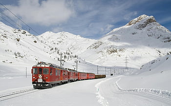 red train, snowy landscape, mountain scenery, clear sky, winter travel, snow-covered field, vibrant red, train journey, alpine view, railway travel, scenic route