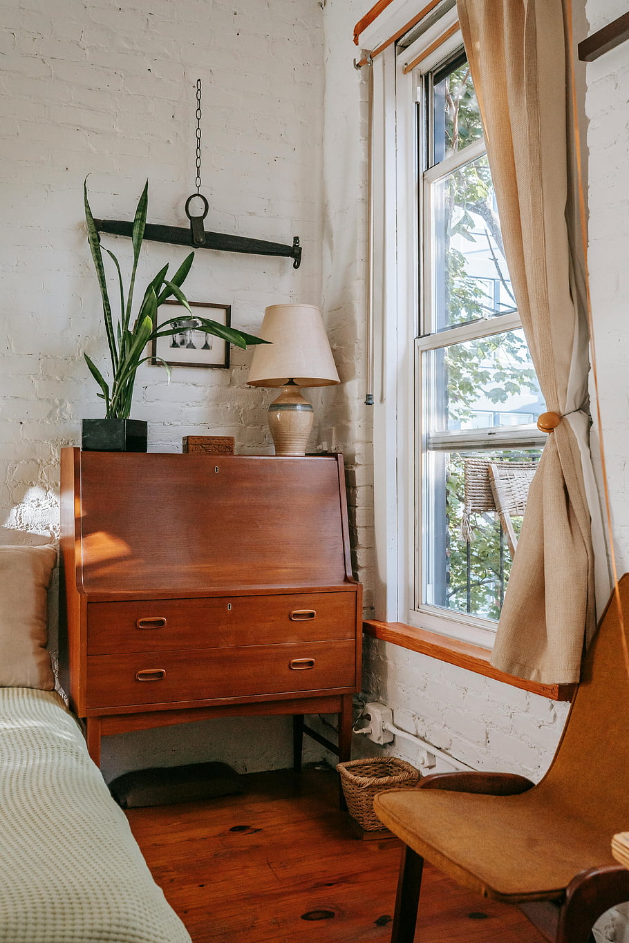 stará ložnice, Vintage dřevěný stůl, rostliny podle okna, teplá ložnice, Pozvící ložnici, cihlová zeď, dřevěná podlaha, útulný interiér, přirozené světlo, Retro nábytek, zobrazení okna