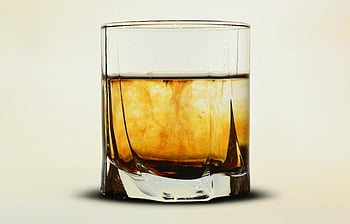 clear glass, brown liquid, amber whiskey, close-up, soft neutral backdrop, beverage themes, whiskey glass, neutral background, drink photography, alcoholic beverage, glassware