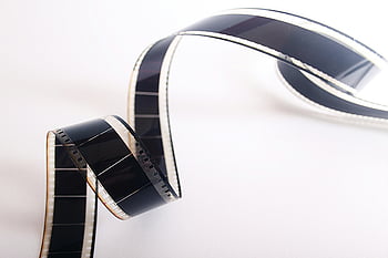 spiral film strip, curled filmstrip, vintage cinema, close-up, white background, film photography, retro film, classic film, film reel, movie film, analog film