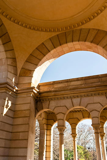 arched passage, columns, aged building, ornate stone archways, blue sky, European architecture, architectural beauty, stone columns, arched structure, historic building, outdoor archway