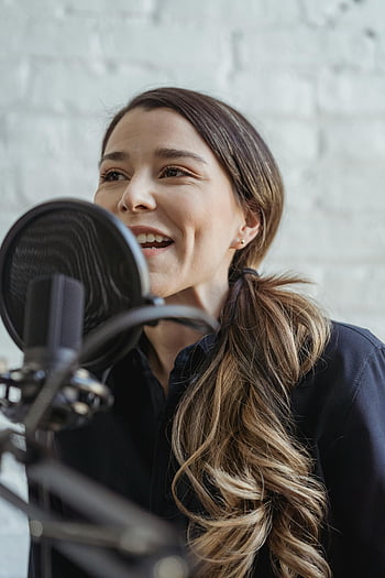 Szczęśliwa kobieta, Nagrywanie podcastów, nowoczesne studio, uśmiechnięta kobieta, casualowy strój, mówienie mikrofonu, ustawienie studyjne, Profesjonalne nagranie, Produkcja dźwięku, Twórca treści, Kobieta podcaster