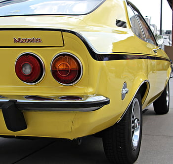 yellow Manta, vintage car, classic design, daytime, close-up view, yellow muscle car, black stripe, rear view, classic features, parked car, yellow vehicle
