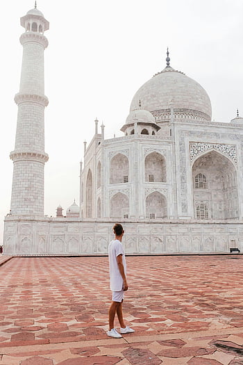 Taj Mahal, man standing, stunning architecture, cloudy sky, tourist attraction, India landmark, white marble, minaret, travel destination, historic monument, Agra
