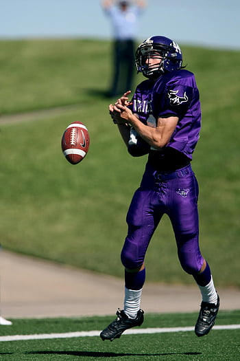 Football americano, giocatore che cattura la palla, giochi all'aperto, giorno soleggiato, maglietta da calcio, azione sportiva, prestazioni atletiche, Gioco sul campo, sport competitivi, momento di gioco, giocatore in azione