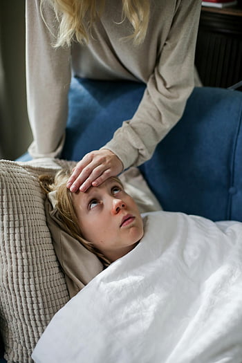 Chlapec leží na gauči, malé dítě, pod přikrývkou, Kontrola teploty pečovatele, uvnitř, nemocné dítě, matka kontroluje teplotu, dítě odpočívá, Couch Rest, Vnitřní péče, Pomoc pečovatelů