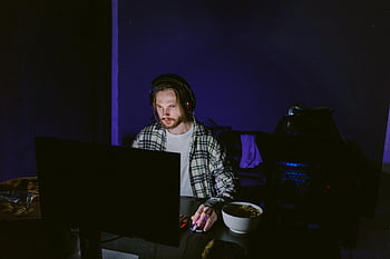 Mies ruudullinen paita, Videopelien pelaaminen, tietokonepelaaminen, keskittynyt pelaaja, yöpeli, kuulokkeet, videopelaaja, ruudullinen paita, tietokoneen näyttö, peliasetukset, pimeä huone