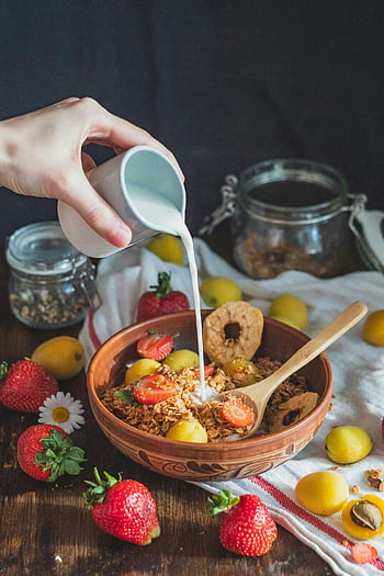 breakfast bowl, pouring milk, granola, strawberries, plums, cereal, fruit, vibrant breakfast, wooden bowl, wooden spoon, healthy breakfast