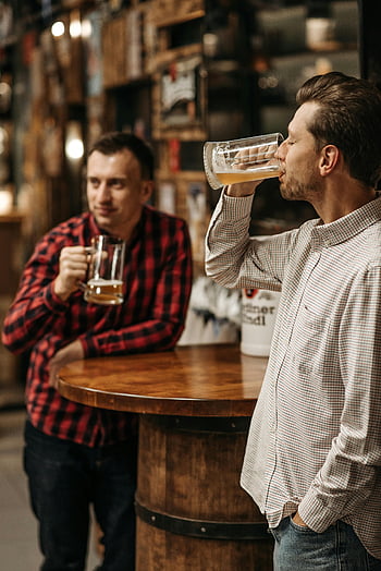 men drinking beer, two friends, bar, draft beer, cozy setting, relaxing, wooden table, plaid shirt, casual attire, socializing, drinks