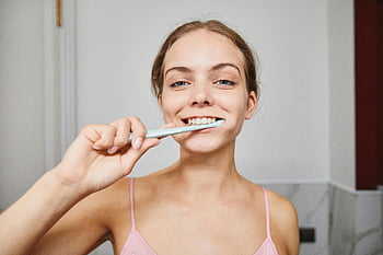 woman brushing teeth, close-up shot, modern bathroom, smiling woman, dental hygiene, toothbrush, oral care, personal care, morning routine, healthy teeth, bathroom setting