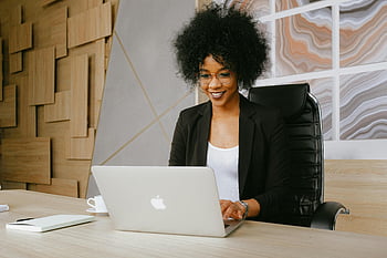 donna in blazer nero, seduto per tavolo, Usando MacBook, donna sorridente, lavorando da remoto, il computer portatile, Elegante impostazione dell'ufficio, Abbigliamento professionale, ambiente di ufficio, lavoro a distanza, donna d'affari