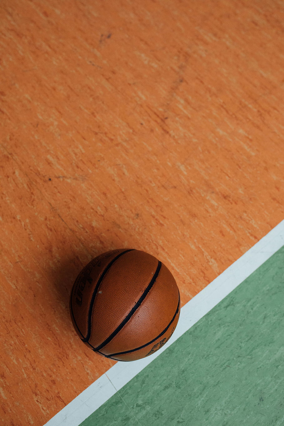 basketball, indoor court, orange flooring, green flooring, close-up, sports ball, vibrant colors, sports equipment, gymnasium, sports photography, recreation