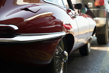 Red Car, Gray Surface, classic Jaguar XK E, coupe, shiny chrome details, urban setting, close-up, classic car, chrome trim, vintage automobile, Jaguar E-Type