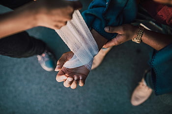 bandage, injured wrist, outdoor scene, hands applying, detail shot, medical care, first aid, outdoor assistance, wrist injury, bandage application, outdoor medical care