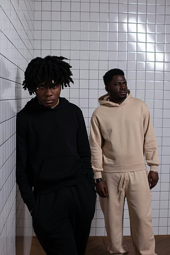 African American men, confident men, tiled wall, stylish black men, casual hoodies, minimalist setting, two men posing, black men fashion, urban style, modern fashion, confident pose