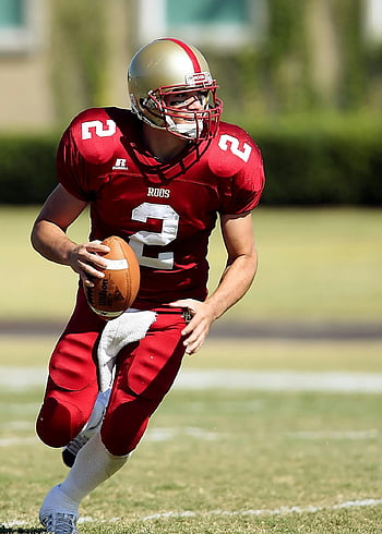 Fußballspieler, Laufen, grünes Feld, tagsüber, Quarterback, Roter Trikot, Fußball, Grasiges Feld, Sportveranstaltung, Roos, Action-Schuss