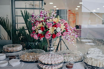 Blumen in der Vase, lebendiges blumiges Herzstück, rosa Rosen, rote Rosen, Esstisch eingerichtet, Innenveranstaltung, Blumengesteck, Veranstaltungsdekor, Tafelaufsatz, Vielzahl von Blumen, Indoor Blumen