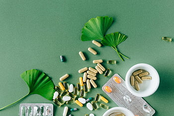 flat lay, alternative medicines, supplements, ginkgo leaves, natural remedies, green surface, varied medicines, health products, herbal supplements, vitamin capsules, flat lay photography
