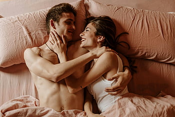 couple, lying down, bed, intimate embrace, joyful moment, close-up shot, together, love, pink bedding, affectionate, happiness