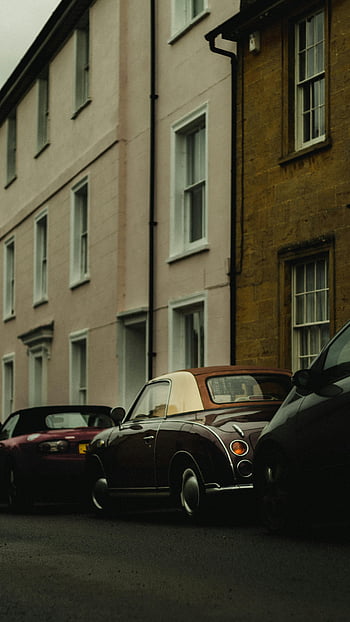 klassisches Auto, Nissan Figaro, geparkte Straße, ruhige Straße, farbenfrohe Gebäudefassaden, Oldtimer, Retro Auto, städtische Szene, Autofotografie, Strassenfotografie, klassisches Fahrzeug