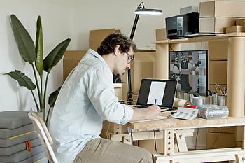 businessman, online store, home office, typing laptop, packaging supplies, writing paper, desk setup, work from home, small business, e-commerce, cardboard boxes
