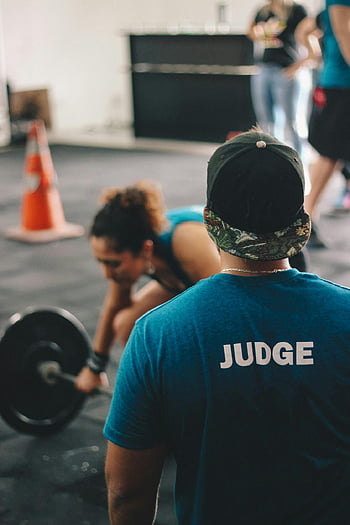 CrossFit, giudice, atleta femminile, Evento di sollevamento pesi, palestra interna, manubrio, camicia da scollo a squadre blu, CrossFit Judge, allenamento indoor, competizione di sollevamento pesi, bilanciere di sollevamento della donna