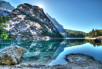 mountain lake, crystal-clear reflections, serene water, bright daytime sky, natural landscape, outdoor scenery, calm waters, alpine lake, scenic view, peaceful environment, nature photography