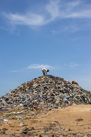 man working, garbage dump, mound of garbage, bright blue sky, pollution, environmental issues, waste management, landfill, plastic waste, recycling, sustainability